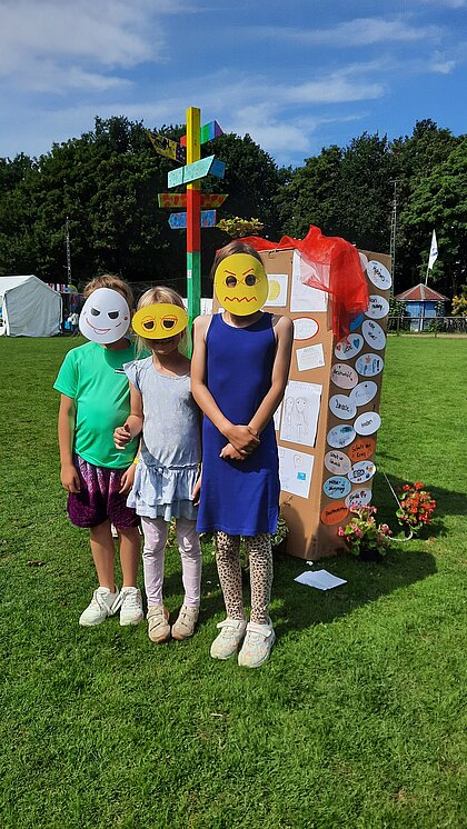 Platz der Kinderrechte im Hintergrund mit Wegweiser und Infotafel, im Vordergrund beteiligteKinder