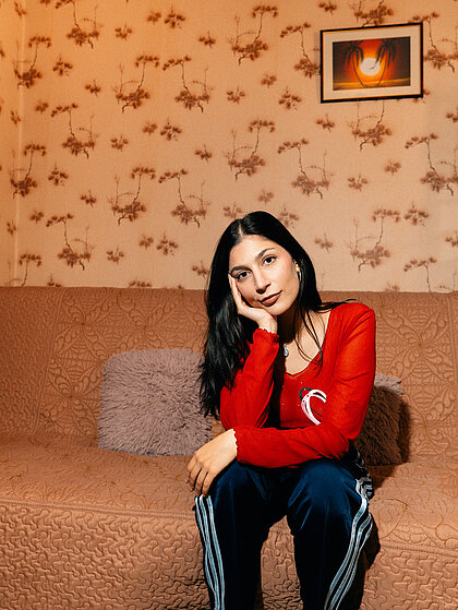 Eine Person sitzt auf einem Sofa und schaut in die Kamera